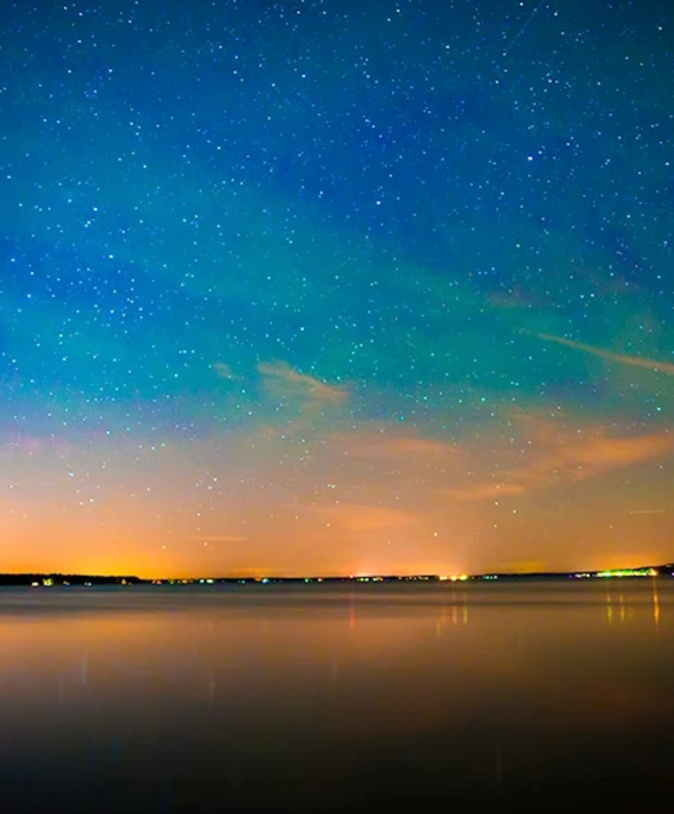 Night sky filled with stars reflected over a calm Minnesota lake