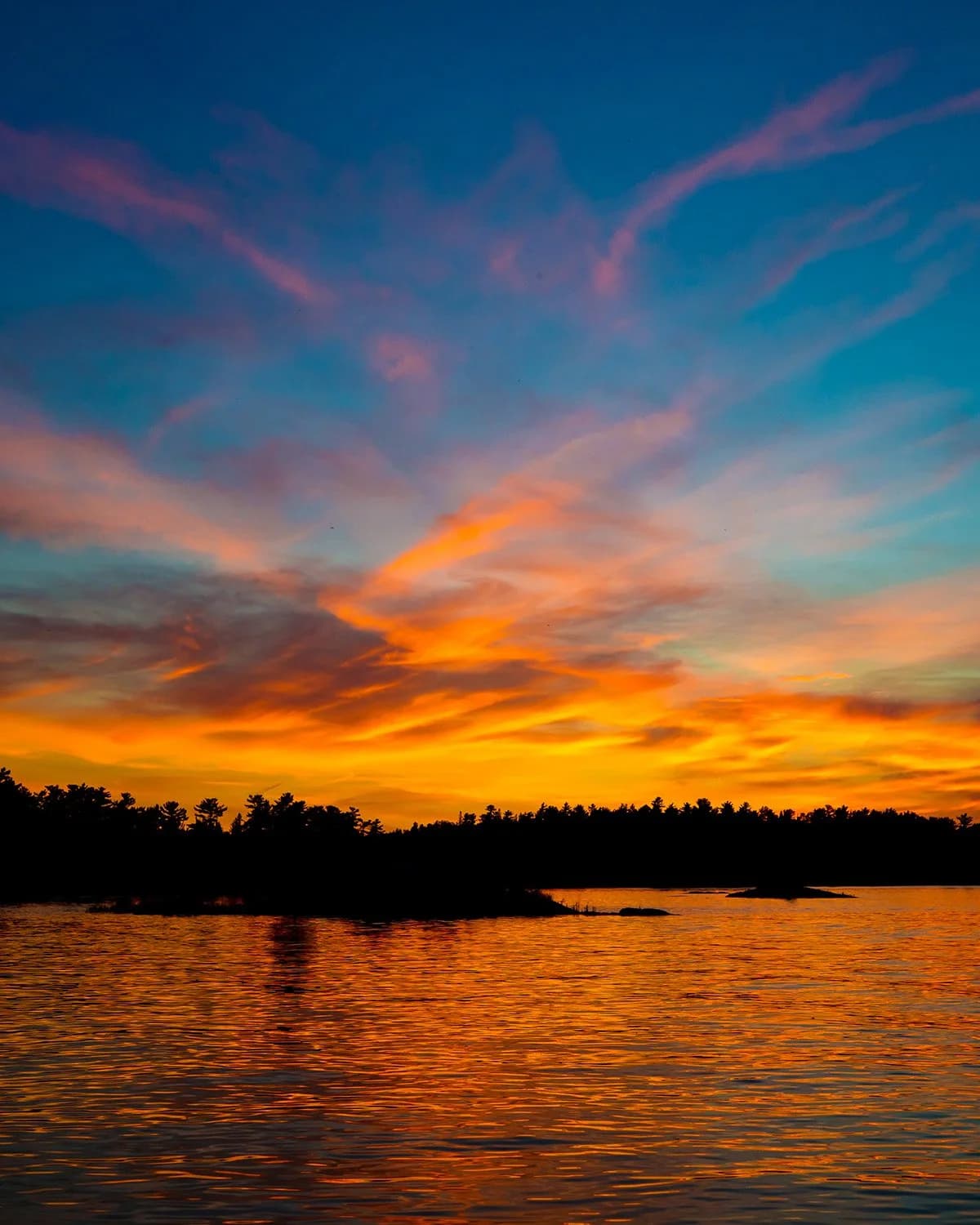Vibrant sunset over a Minnesota lake with colorful clouds and silhouetted trees